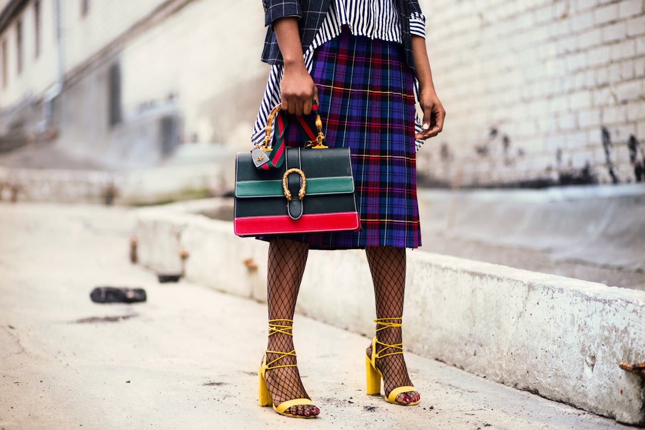 Home Fashion-forward outfit with plaid skirt and colorful handbag in urban setting.